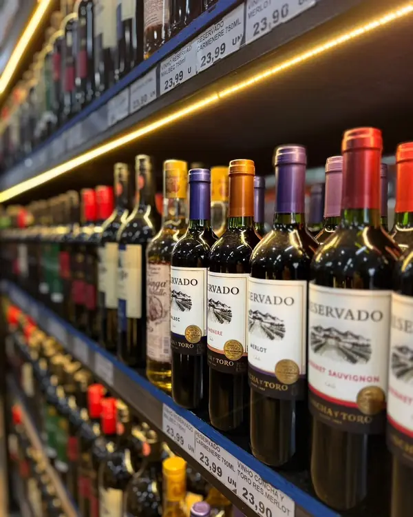 Interior da Bebidas Damião: prateleira de vinhos iluminada com LED